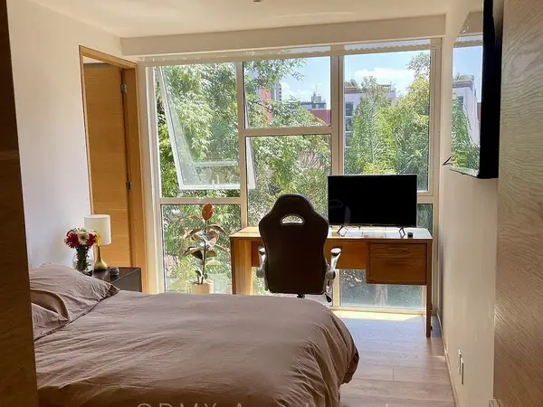Bedroom with a wall of windows facing the trees